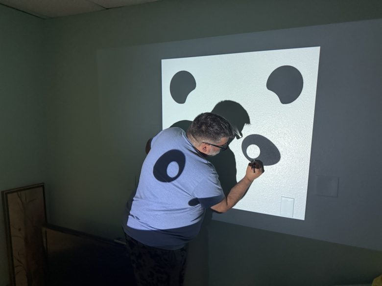 A man painting the Peaceful Panda Massage logo